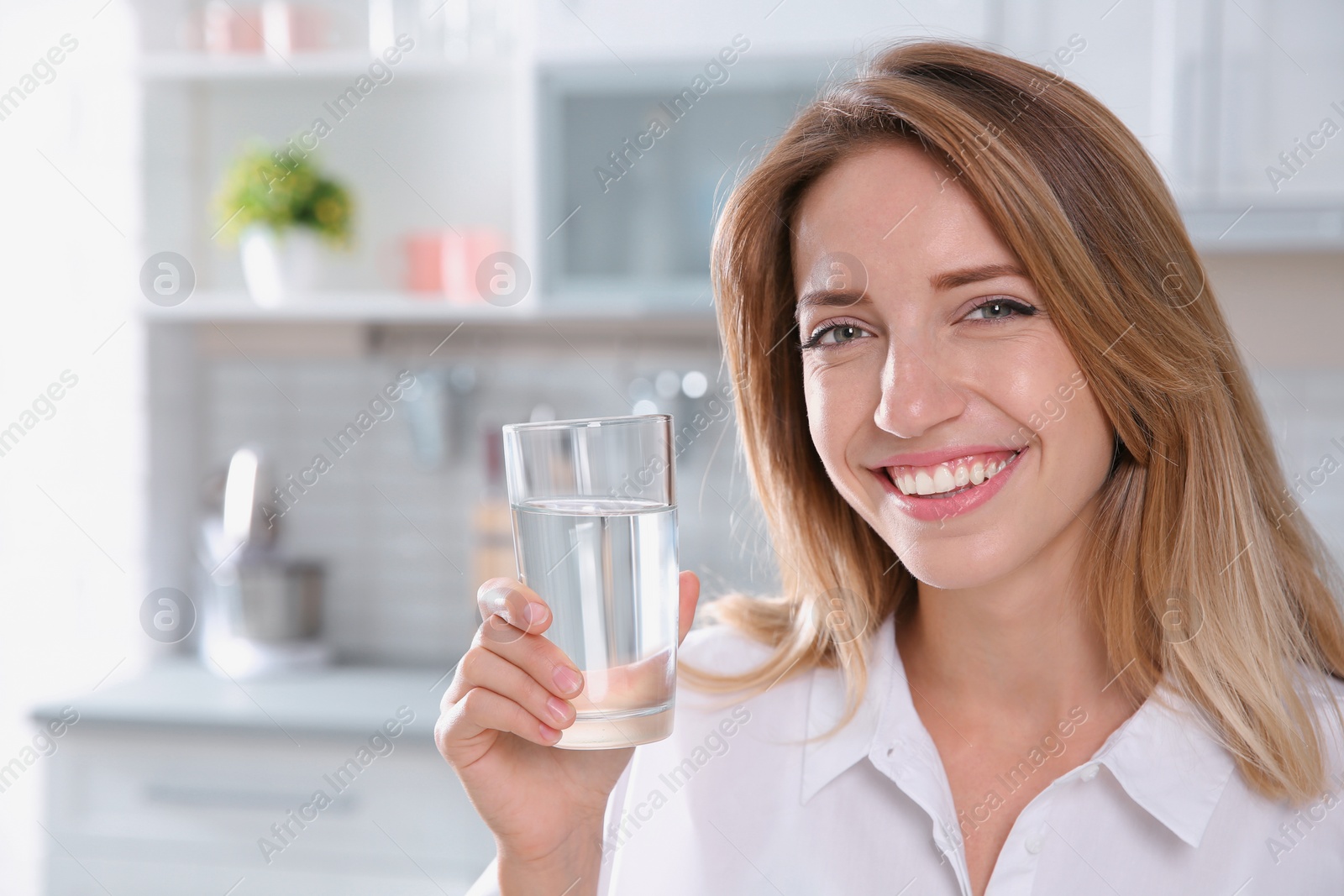 Photo of Young woman holding glass with clean water in kitchen