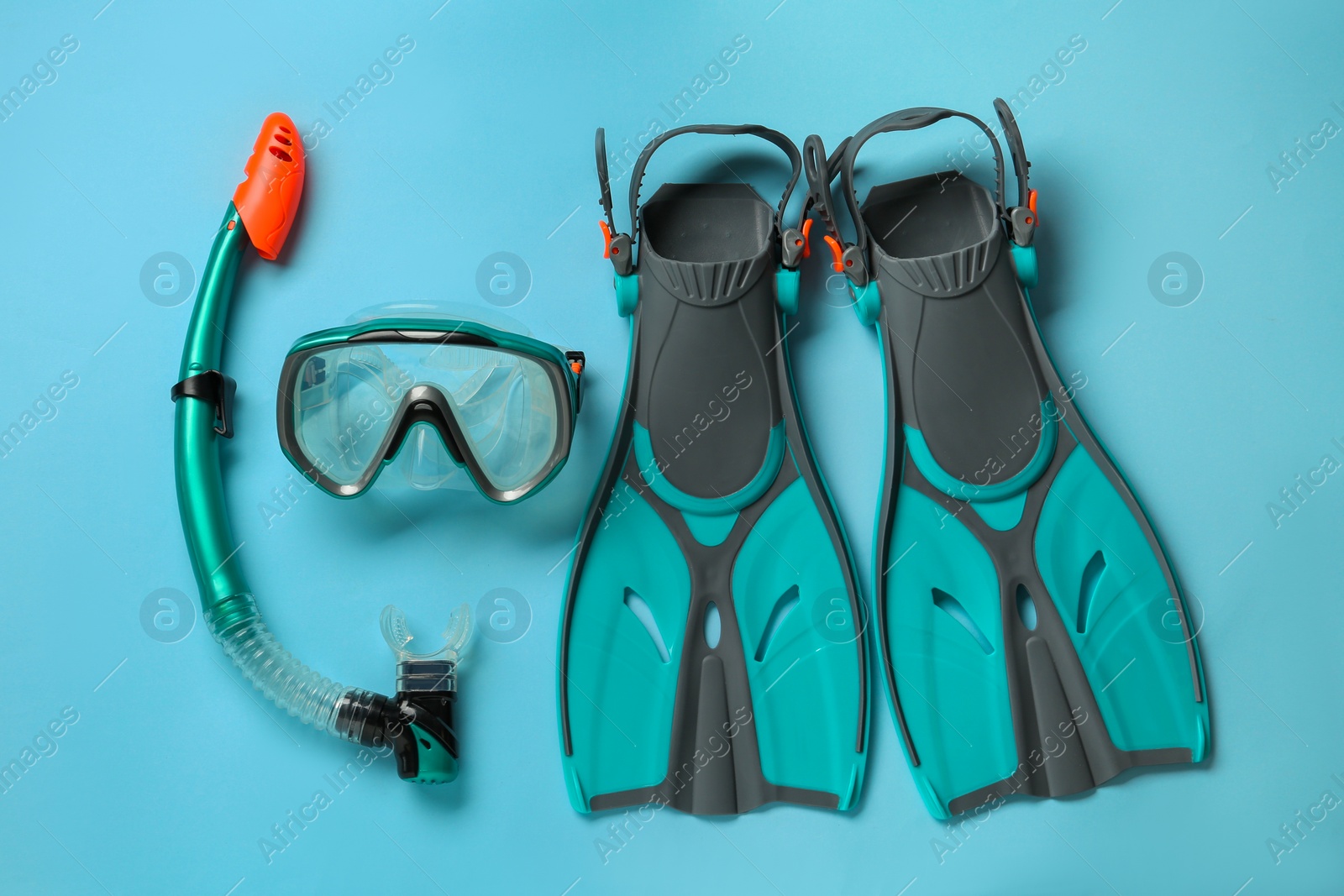 Photo of Pair of turquoise flippers and mask on light blue background, flat lay