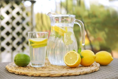 Water with lemons and limes on table outdoors