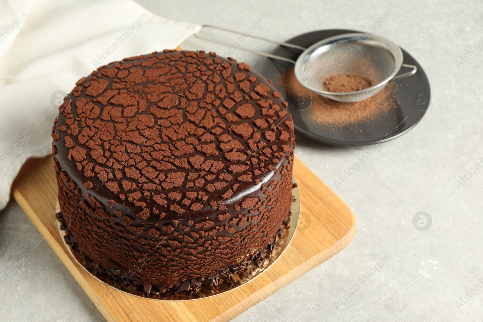 Photo of Delicious chocolate truffle cake and cocoa powder on light grey table