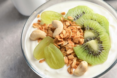 Photo of Bowl with yogurt, fruits and granola on table, closeup