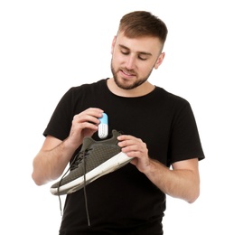 Photo of Young man putting capsule shoe freshener in footwear on white background