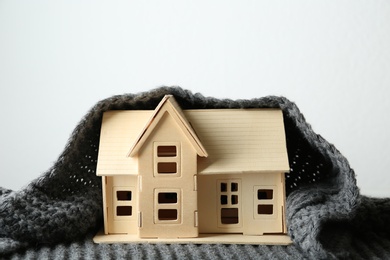 Photo of Wooden house model and scarf on white background. Heating efficiency