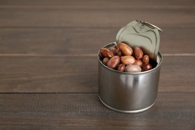 Photo of Tin can with kidney beans on wooden table, space for text