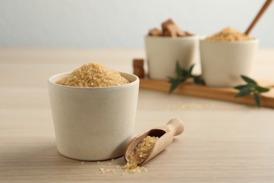 Photo of Brown sugar in bowl and scoop on wooden table. Space for text