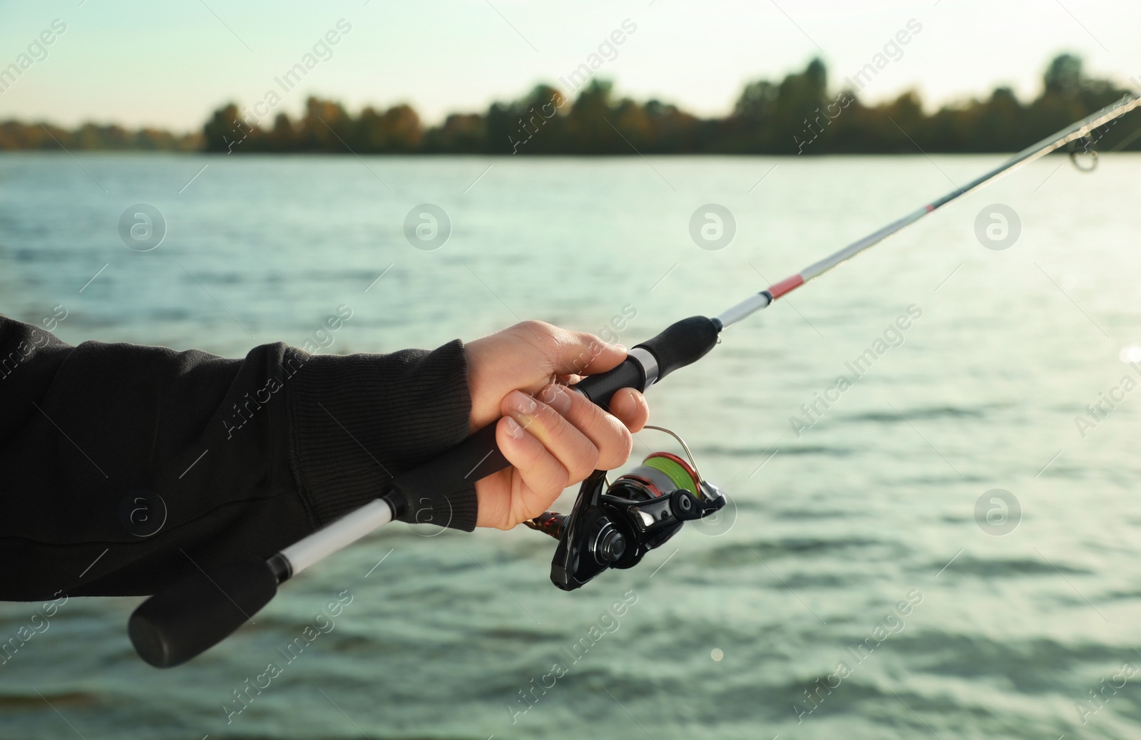 Photo of Fisherman with rod fishing at riverside, closeup