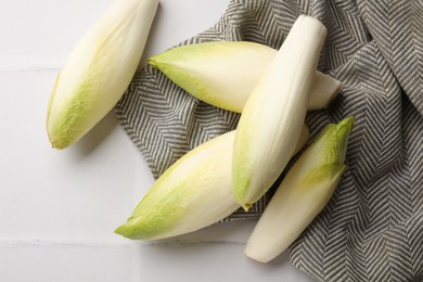 Photo of Fresh raw Belgian endives (chicory) on white tiled table, top view