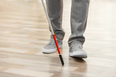 Photo of Blind person with long cane walking indoors, closeup. Space for text