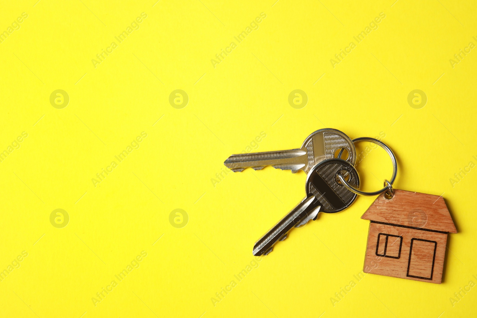 Photo of House keys with trinket on color background, top view. Space for text