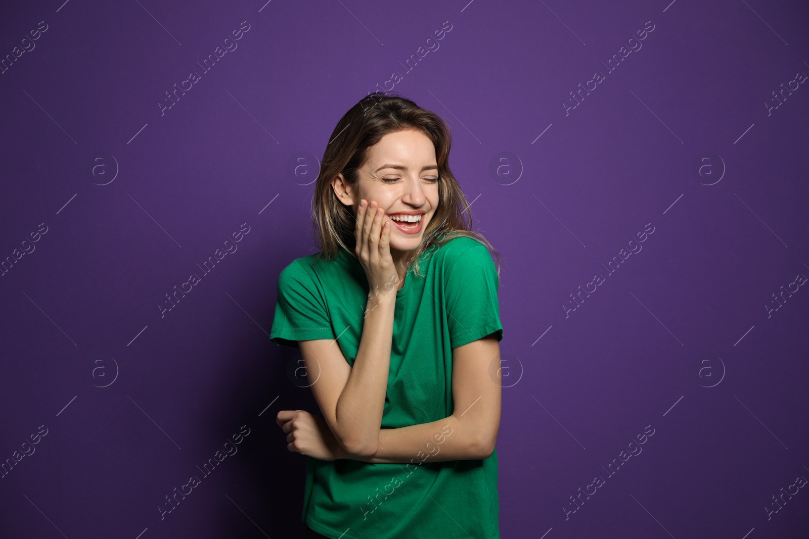 Photo of Cheerful young woman laughing on violet background