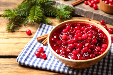 Photo of Fresh cranberry sauce in bowl on wooden table, space for text