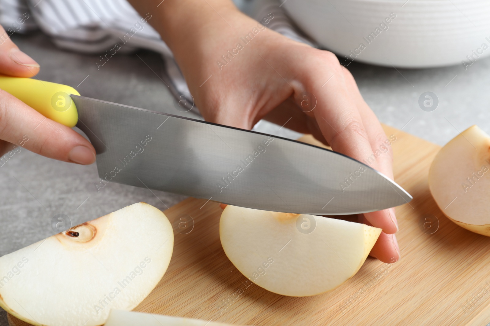Photo of Woman cutting apple pear at grey table, closeup