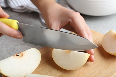 Photo of Woman cutting apple pear at grey table, closeup