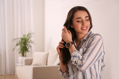 Photo of Young woman with smart watch at home, space for text