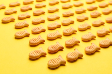Photo of Delicious goldfish crackers on yellow background, closeup