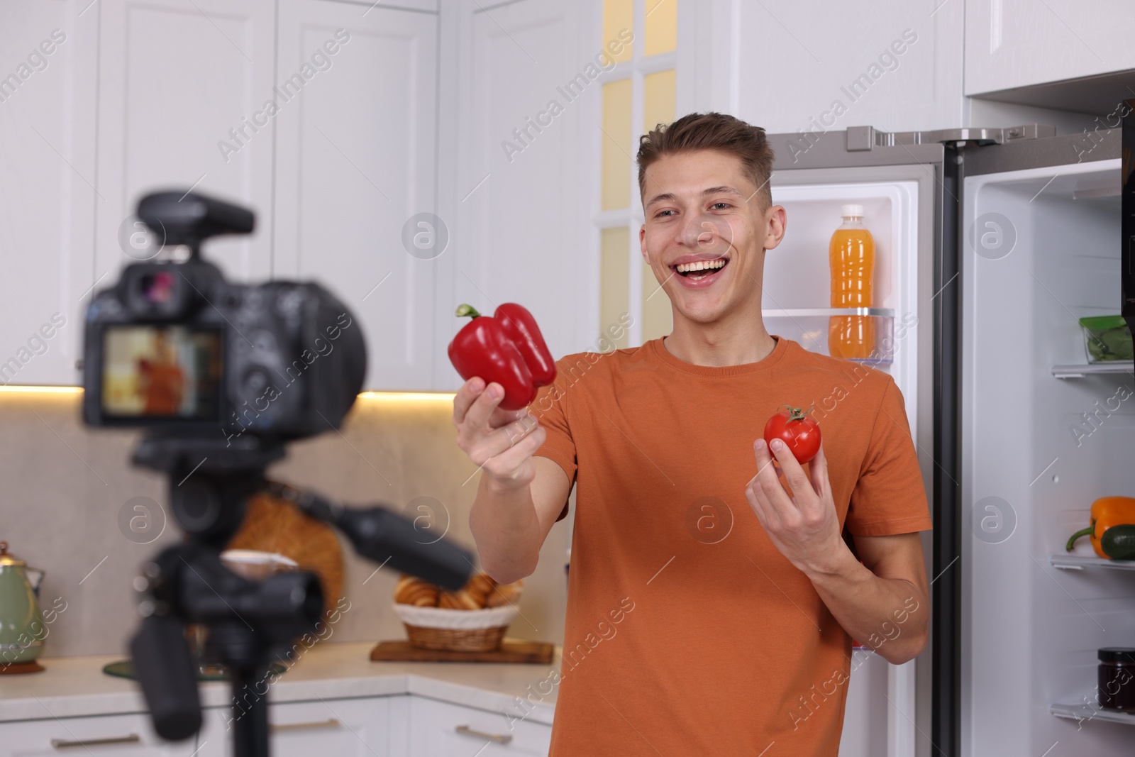 Photo of Smiling food blogger explaining something while recording video in kitchen