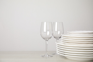 Photo of Stack of clean plates and glasses on table against white background. Space for text