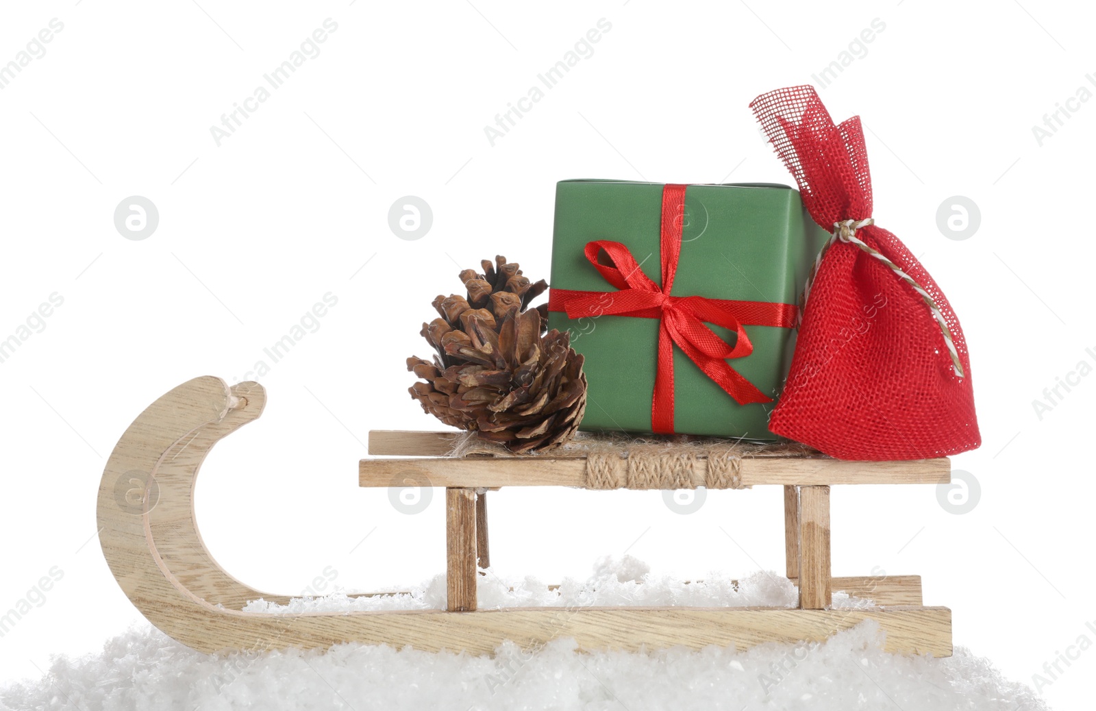 Photo of Wooden sleigh with Christmas gifts, pine cone and artificial snow on white background