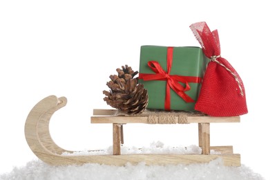 Wooden sleigh with Christmas gifts, pine cone and artificial snow on white background