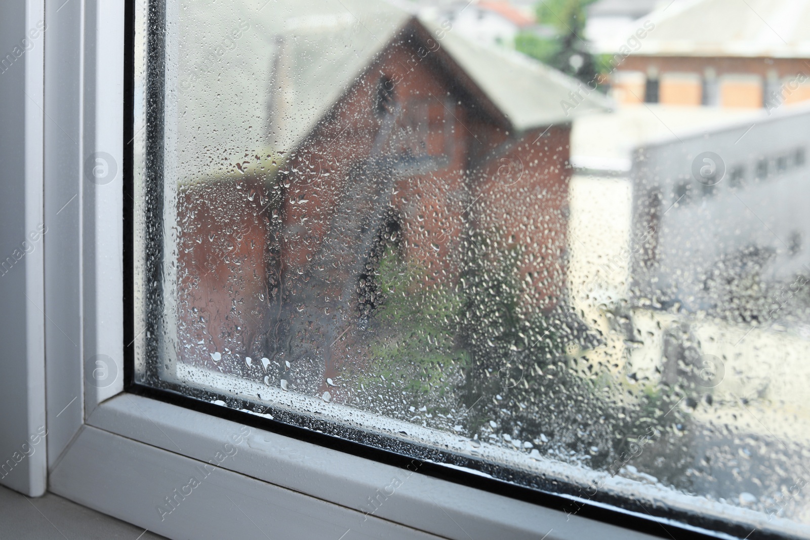 Photo of Wet window on rainy day, closeup. View from inside