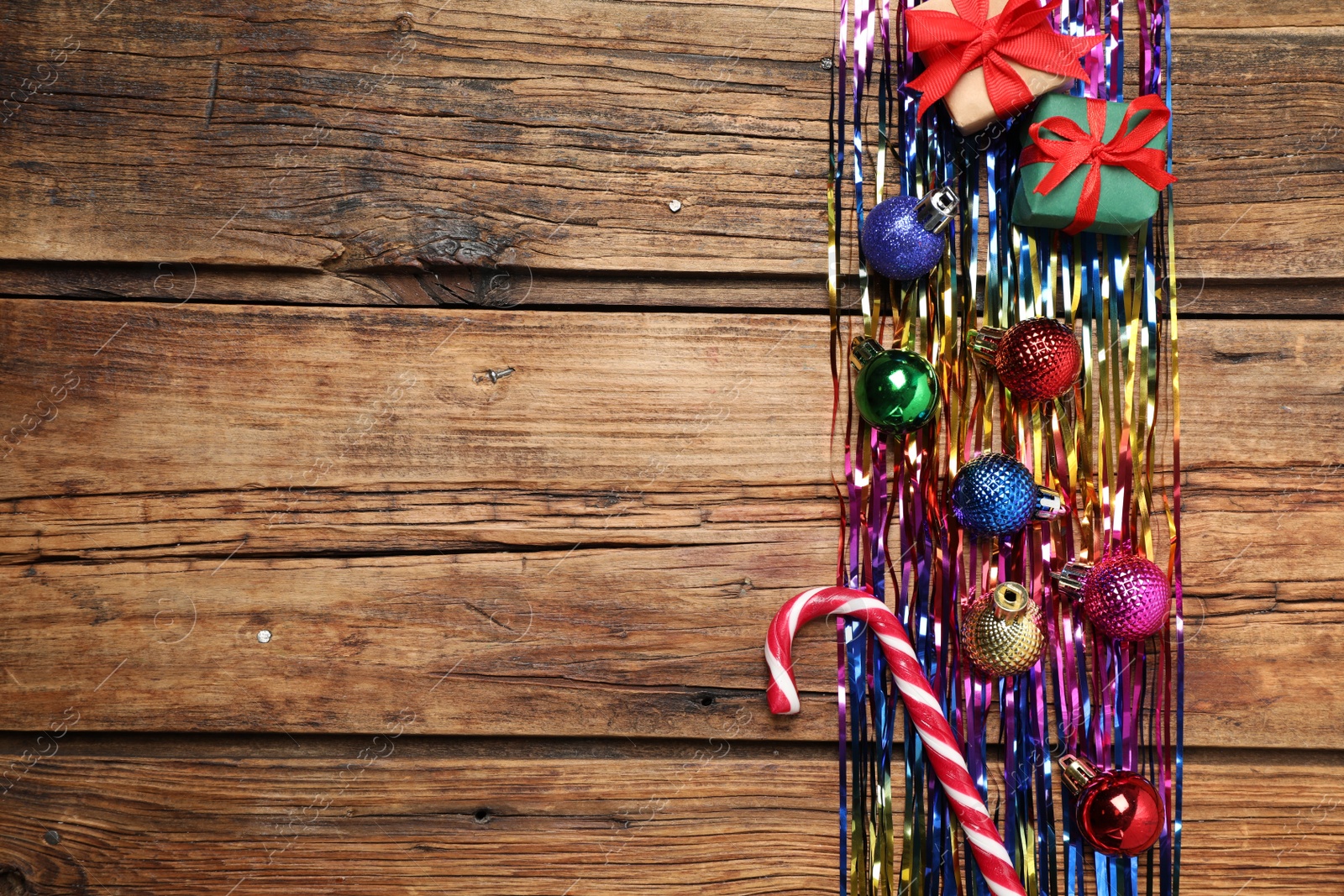 Photo of Bright tinsel and Christmas decor on wooden background, flat lay. Space for text