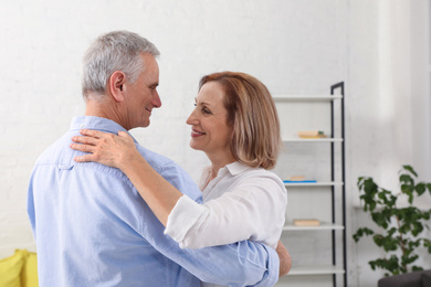 Photo of Happy senior couple dancing together in living room