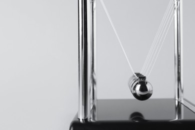 Photo of Newton's cradle on light background, closeup. Physics law of energy conservation