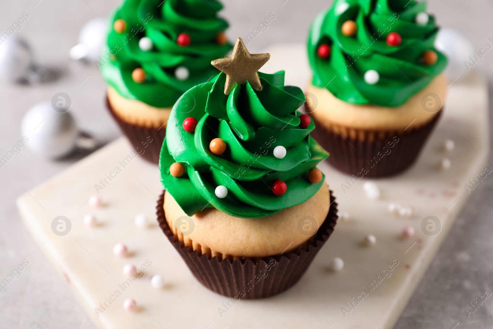 Photo of Christmas tree shaped cupcakes on light grey table, closeup