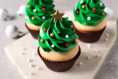 Christmas tree shaped cupcakes on light grey table, closeup