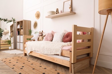 Photo of Cute child's room interior with comfortable bed and toys