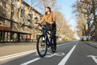 Handsome man riding bicycle on lane in city