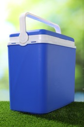 Photo of One plastic cool box on artificial grass, closeup