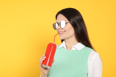 Photo of Beautiful happy woman drinking from red beverage can on yellow background. Space for text