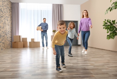 Photo of Happy family and pile of moving boxes in their new house