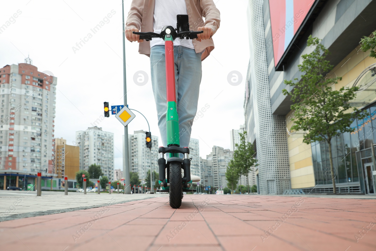 Photo of Man riding modern electric kick scooter on city street, closeup