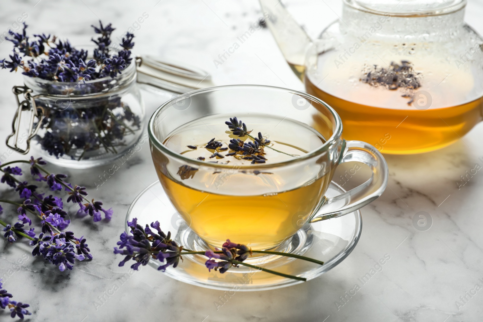 Photo of Fresh delicious tea with lavender and beautiful flowers on white marble table