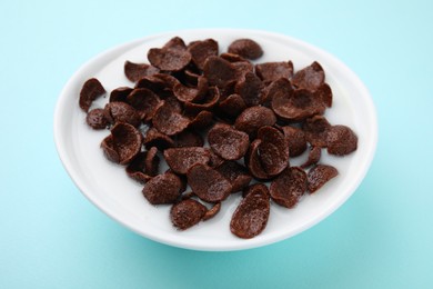 Photo of Breakfast cereal. Chocolate corn flakes and milk in bowl on turquoise background, closeup