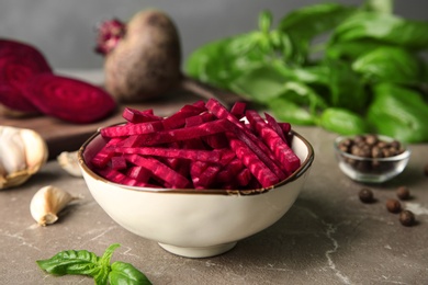 Photo of Bowl of cut fresh beets with basil and allspice on table