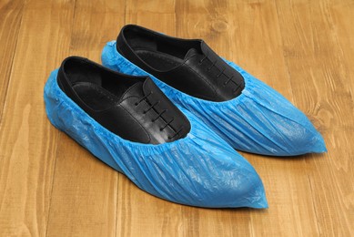 Photo of Men`s black shoes in blue shoe covers on wooden floor