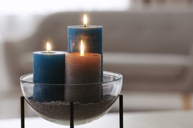 Bowl with burning candles on blurred background. Space for text