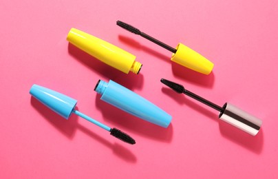 Photo of Different mascaras on bright pink background, flat lay