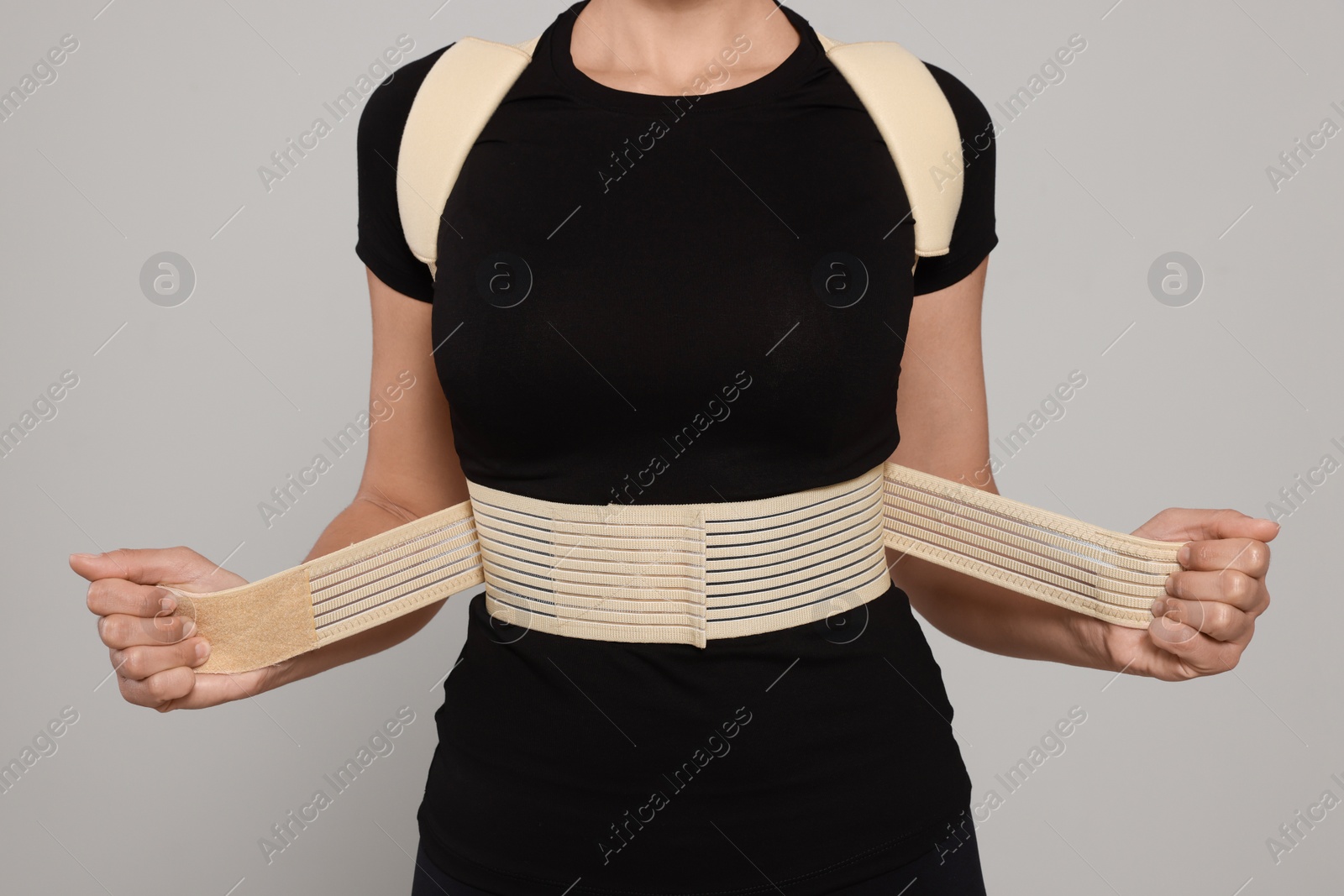 Photo of Closeup view of woman with orthopedic corset on grey background
