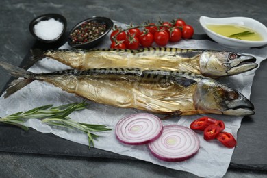 Photo of Delicious smoked mackerels and products on grey table, closeup