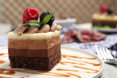 Piece of triple chocolate mousse cake with fresh berries on table, closeup. Space for text