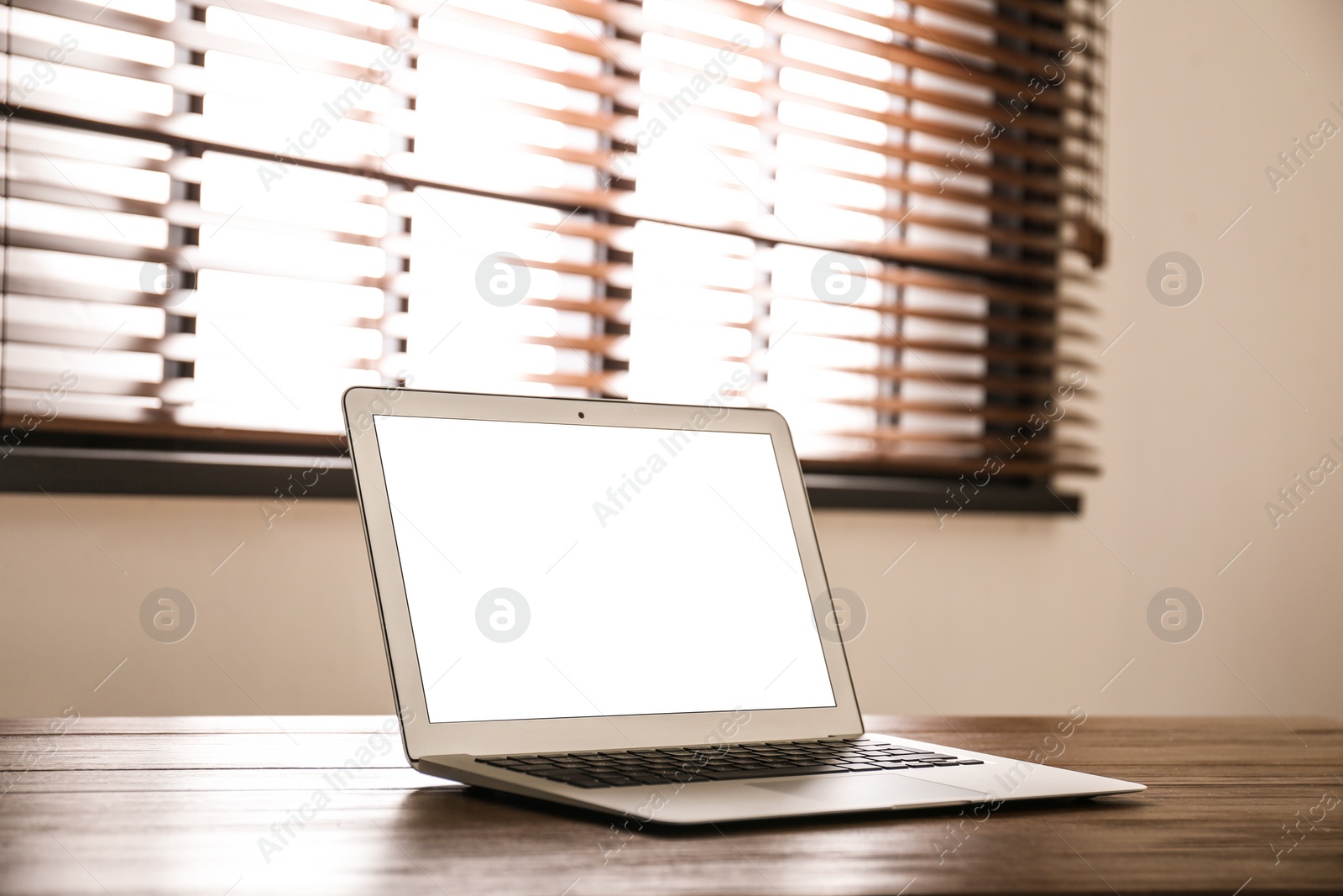 Photo of Modern laptop with blank screen on table in room