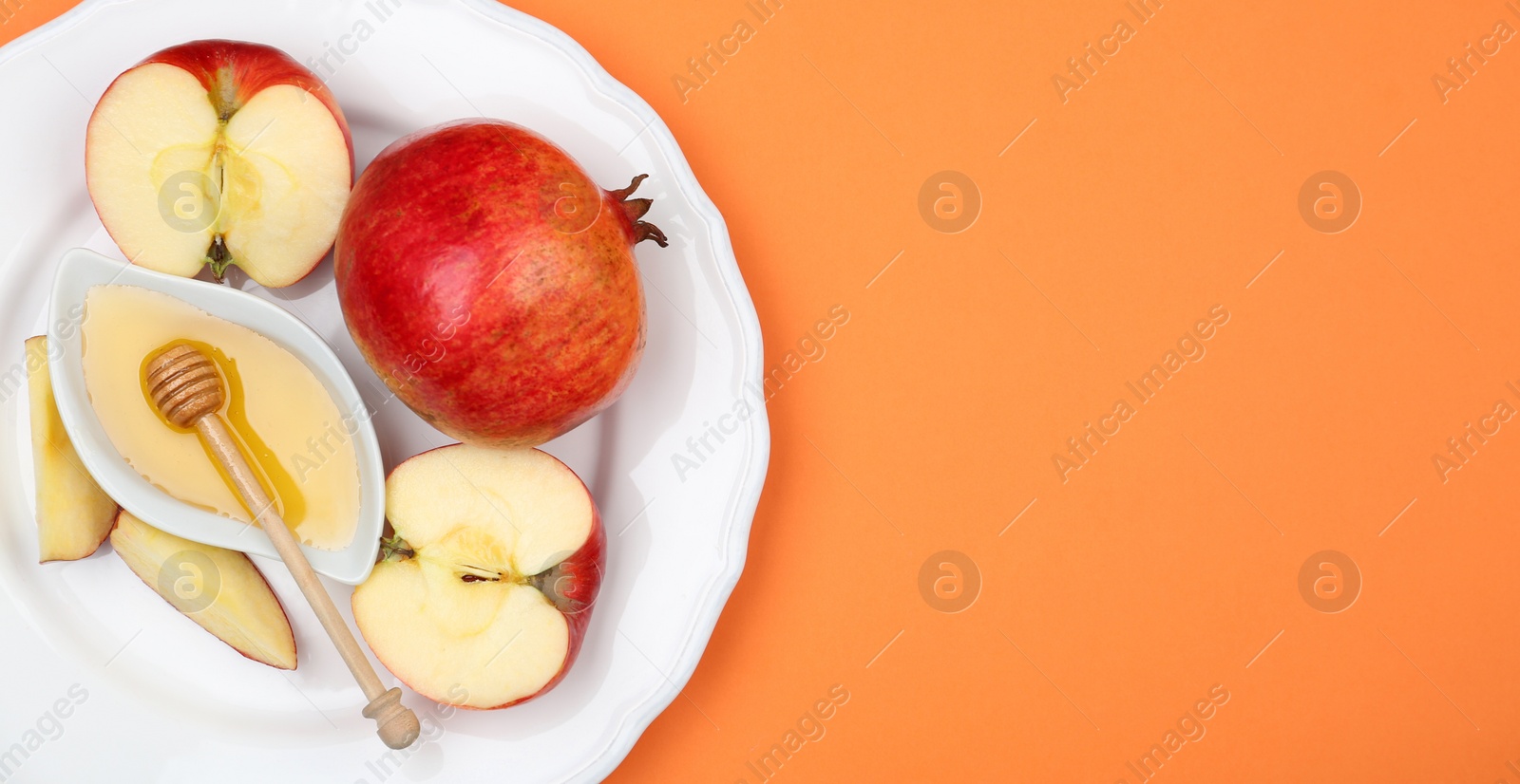 Photo of Honey, apples and pomegranate on orange background, top view. with space for text Rosh Hashanah holiday