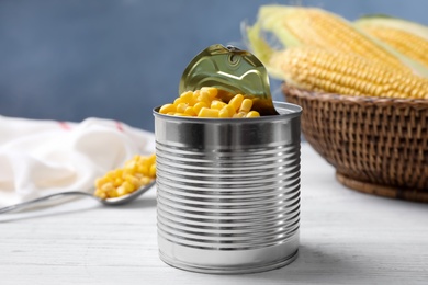 Photo of Can of preserved corn on white wooden table