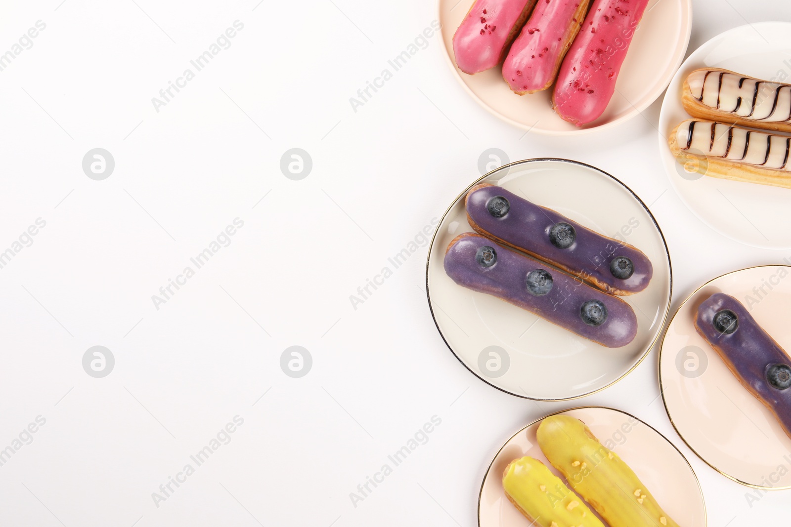 Photo of Delicious eclairs covered with glaze on white background, top view