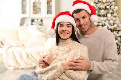 Photo of Happy couple in Santa hats at home. Christmas celebration