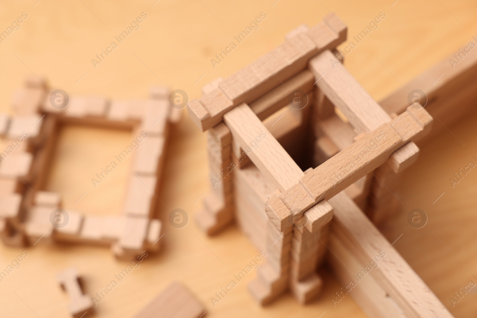 Photo of Wooden fortress and building blocks on table, closeup. Children's toy